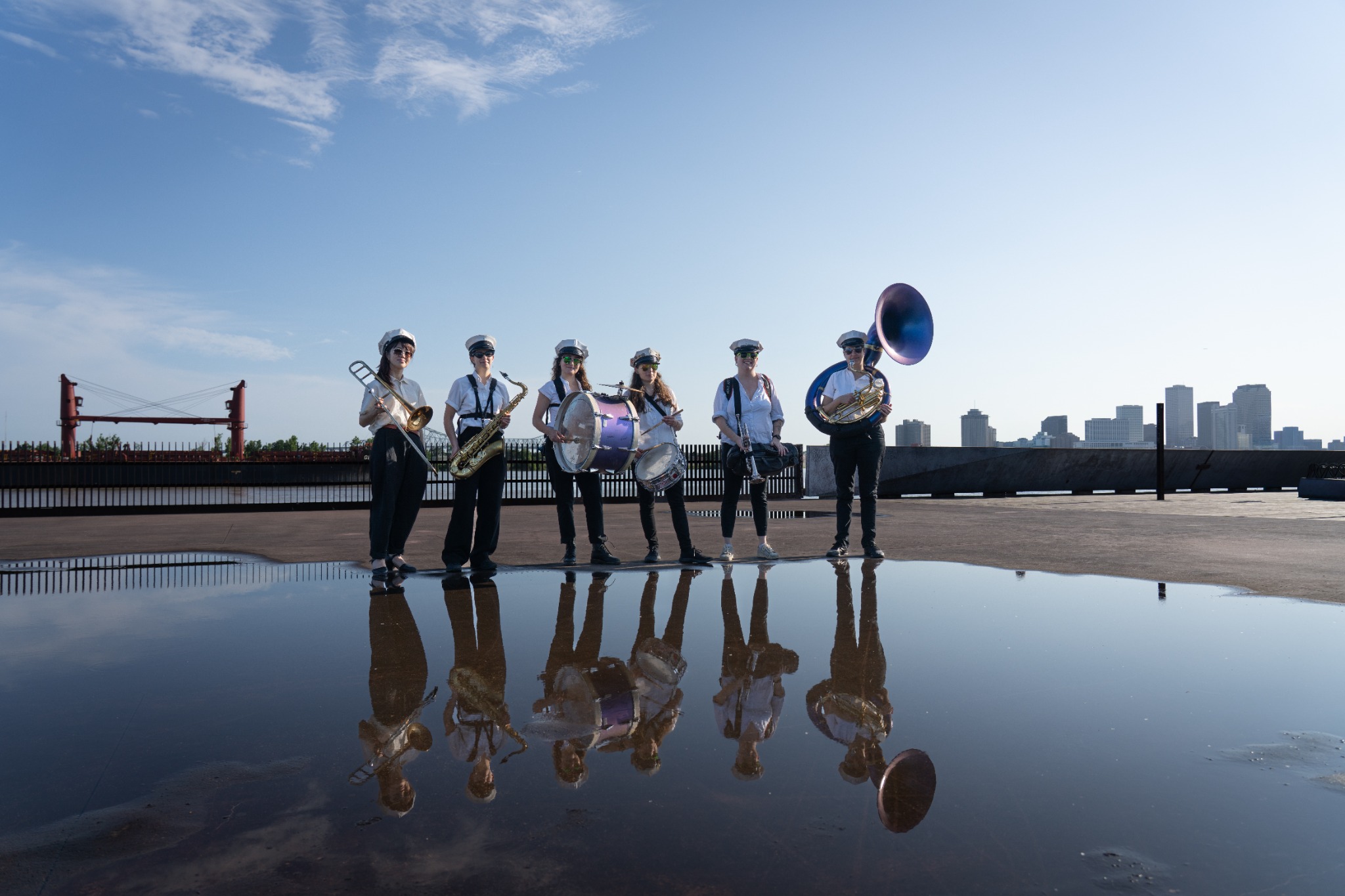 Divas Brass Band, an all-women New Orleans brass band, posing with their instruments and reflections along the New Orleans riverfront